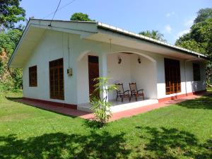 a small white house with two chairs in a yard at Anjana Villa in Hikkaduwa