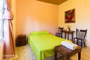 a bedroom with a green bed and a table and chairs at Casa Ricky's in Orange Walk