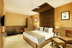 a bedroom with a bed and a desk and a television at The Manor Bareilly by Leisure Hotels in Bareilly