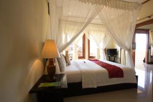 a bedroom with a bed with curtains and a lamp at Arya Amed Beach Resort and Dive Center in Amed +49 photos