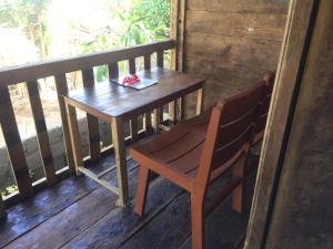 een houten tafel en een stoel op een veranda bij Soka Amed Beach in Amed