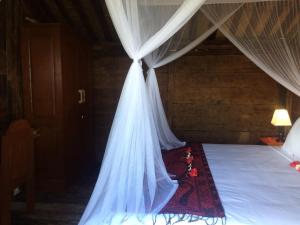 a canopy bed with a white mosquito net at Soka Amed Beach in Amed