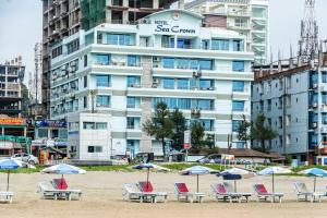 a beach with chairs and umbrellas in front of a building at Hotel Sea Crown in Cox's Bazar