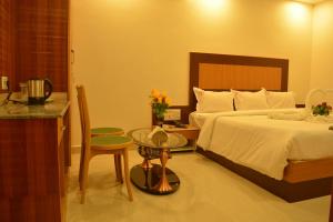 a bedroom with a bed and a table and a chair at Sri Sarvesha Residency Temple view in Tiruvannāmalai