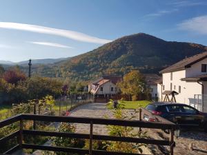 a house with a car parked on a street with a mountain at La Bunica in Cisnădioara