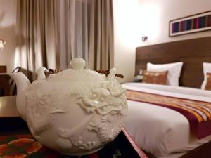 um grande bule de chá branco sentado em frente a uma cama em Utse Suites em Bangalore