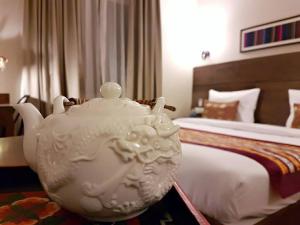 a large white tea pot sitting in front of a bed at Utse Suites in Bangalore