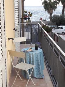 a table and a chair on a balcony with the water at La Casa del Professore in Santa Teresa di Riva