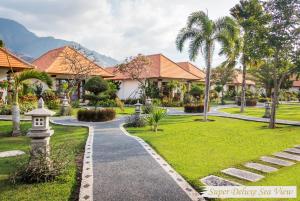 a walkway through a park with palm trees and houses at Adi Assri Beach Resorts And Spa Pemuteran in Pemuteran