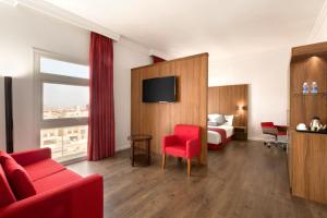 a hotel room with a bed and a red chair at Ramada Encore Al Khobar Olaya in Al Khobar