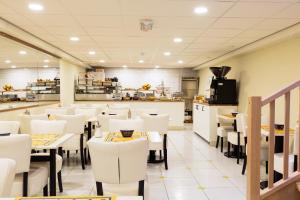 un restaurante con mesas y sillas blancas en Hotel De Looier, en Ámsterdam