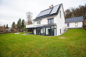 ein weißes Haus mit einem großen Garten mit grünem Gras in der Unterkunft Weinberghaus Prossen in Bad Schandau