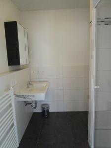 a white bathroom with a sink and a mirror at Haus Meeresblick Wohnung A 1.04 in Baabe