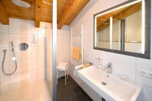 Baño blanco con lavabo y espejo en Landhaus Lenzenhof, en Reit im Winkl