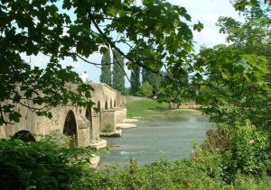 an old bridge over a river with trees at Chambres d'hôtes Le Pont Romain in Montfort-le-Gesnois