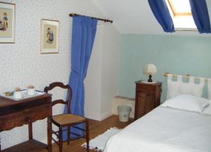 1 dormitorio con cama, escritorio y cortinas azules en Chambres d'hôtes Le Pont Romain, en Montfort-le-Gesnois