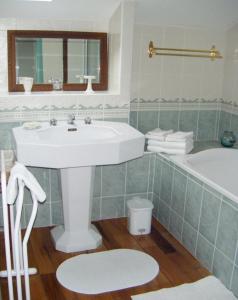 een badkamer met een witte wastafel en een bad bij Chambres d'hôtes Le Pont Romain in Montfort-le-Gesnois