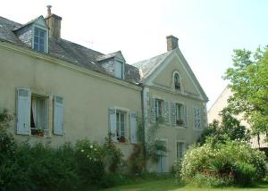 an old white house with blue shutters and plants at Chambres d'hôtes Le Pont Romain in Montfort-le-Gesnois