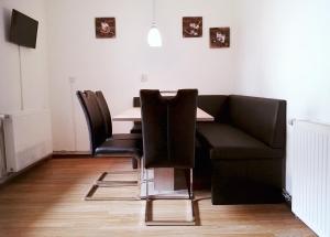 a dining room table with chairs and a couch at Sonntagshof Ferienwohnungen Apartments in Förolach