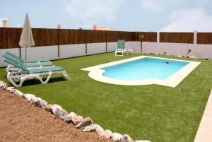 un patio trasero con piscina, una silla y un banco en Ereza Villas Alicia, en Caleta de Fuste