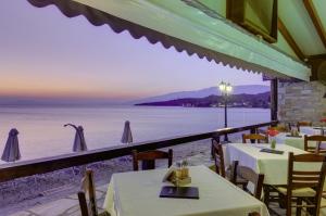 a restaurant with tables and a view of the water at Symmetron Suites in Kalamos