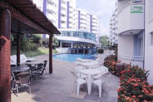 a patio with tables and chairs in front of a building at Prime Hotel Águas da Serra in Rio Quente