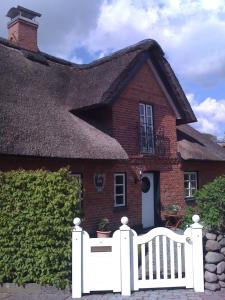 ein Haus mit einem weißen Zaun davor in der Unterkunft CARLS KATE in Grömitz an der Ostsee in Grömitz