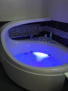 El baño incluye bañera con agua azul. en Au coin du spa, en Boulogne-sur-Mer