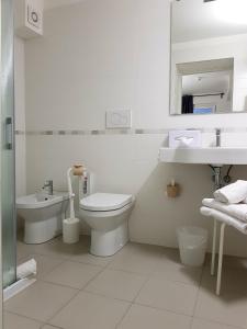 a white bathroom with a toilet and a sink at Hotel Aurora Duino in Duino