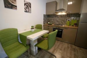 a kitchen with a white table and green chairs at Apartman TARA in Zagreb