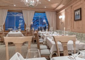 オーバーグルグルにあるホテル アルペンランドの白いテーブルと椅子、シャンデリアのあるレストラン