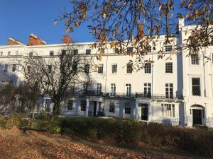 un edificio bianco con un albero di fronte di The Garden Apartment a Leamington Spa