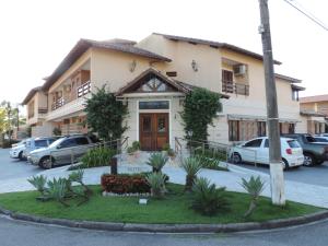 a building with cars parked in a parking lot at Hotel Costa Balena-Piscina Aquecida Coberta in Guarujá