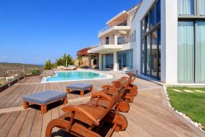 ein Haus mit einer Terrasse mit Stühlen und einem Pool in der Unterkunft Villa TakeOff Saronida in Anavyssos