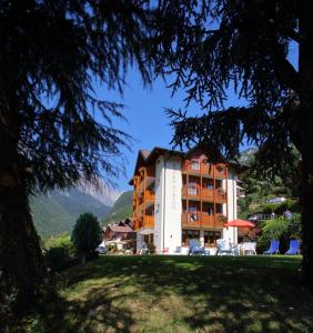 un hôtel situé sur une colline avec une pelouse devant elle dans l'établissement Hotel Zurigo, à Molveno