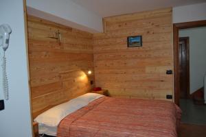 a bedroom with a bed in a room with wooden walls at Albergo Cioccarelli in Aprica