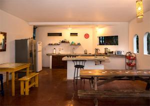 Hostel La Botella de Leche - Tamarindo في تاماريندو: مطبخ مع طاولة وثلاجة