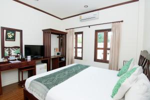 - une chambre avec un lit, un bureau et une télévision dans l'établissement Luang Prabang Legend Hotel, à Luang Prabang