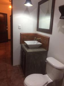 a bathroom with a sink and a toilet and a mirror at Cabañas de Tzununa in Tzununá