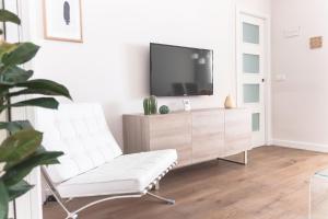 uma sala de estar com uma cadeira branca e uma televisão em ConK Apartments by CasaTuristica em Ronda