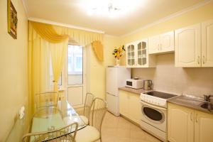 キシナウにあるApartment Deluxe on Moscow Avenueの白いキャビネットとガラスのテーブル付きのキッチン
