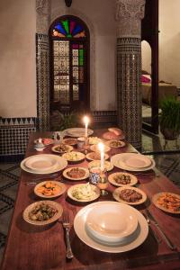 a table with plates of food on it with candles at Dar Drissi in Fez