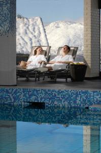 two women sitting in chairs next to a swimming pool at Rauland Høgfjellshotell in Rauland