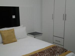 a small bedroom with a bed and a cabinet at Keeme-Nao Self Catering Apartments in Gaborone
