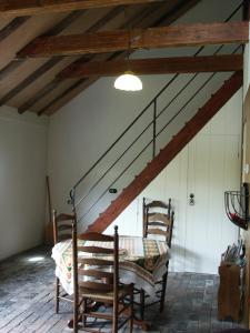 Habitación con mesa, 2 sillas y escalera. en De Wilgenhof, en Finsterwolde