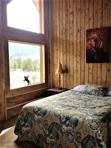 a bedroom with a bed with a dog looking out the window at McDonald's Ranch Lodge in Gardiner