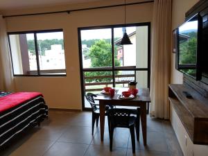 een eetkamer met een tafel, stoelen en ramen bij Studios Formanabá in Florianópolis