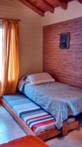 1 dormitorio con cama y pared de ladrillo en Alpamayo en Nono