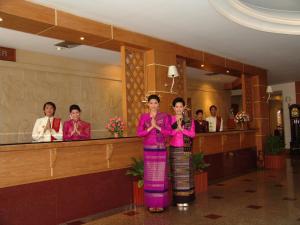 um grupo de mulheres em pé em um lobby vestindo roupões rosa em Dhevaraj Hotel em Nan