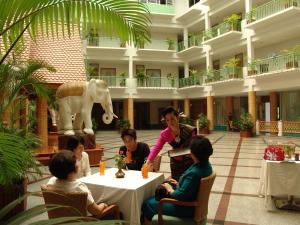 a group of people sitting at tables in a lobby at Dhevaraj Hotel in Nan